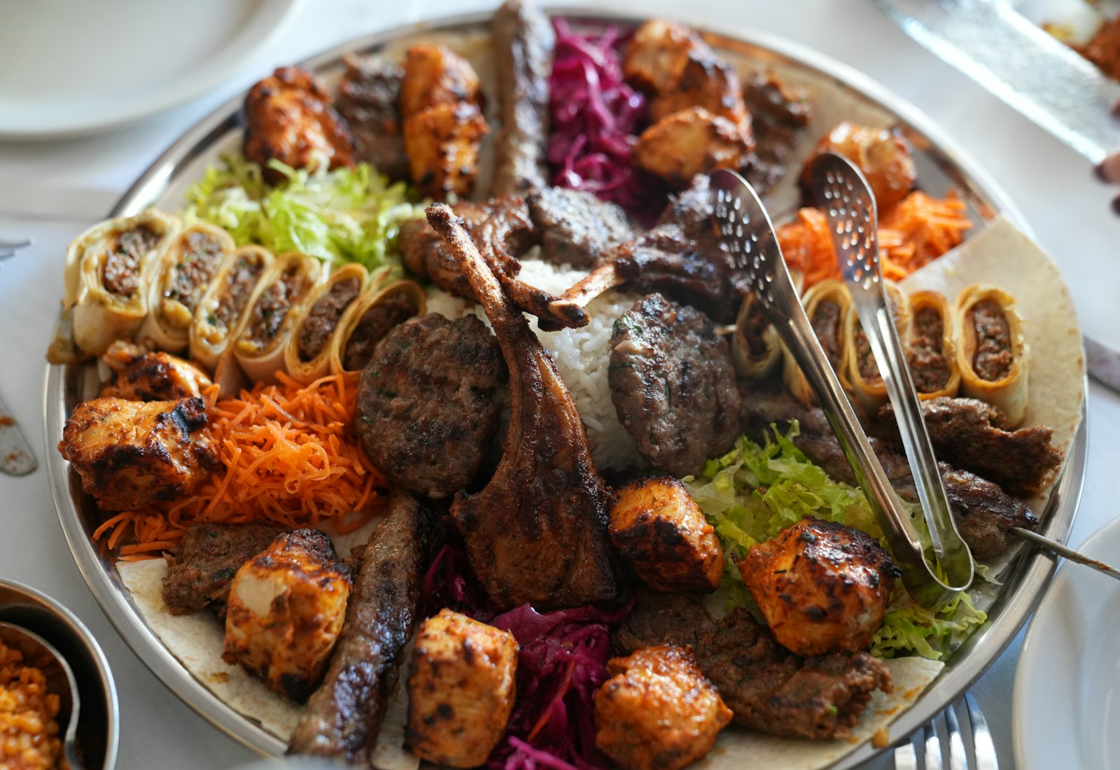 Große Platte mit gegrilltem Fleisch und Grillgemüse auf einem Holztisch