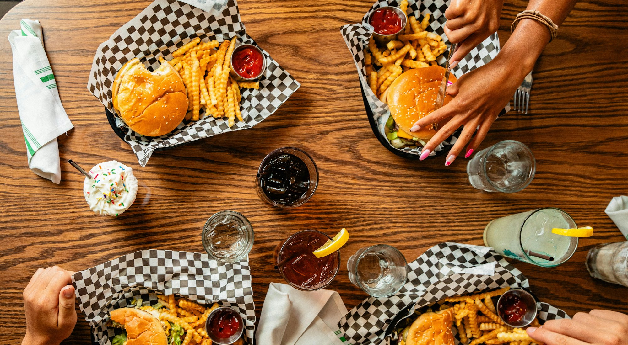 Vier Gäste teilen sich Essen an einem Holztisch im Lokal